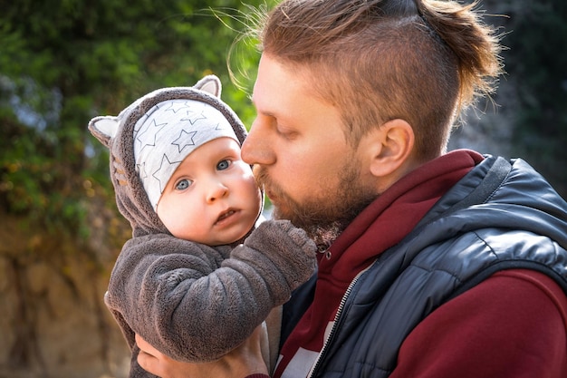 Foto giovane padre hipster con il suo neonato ritratto all'aperto l'uomo sta portando il suo bambino e viaggia nella natura