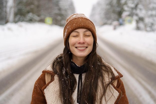 Giovane ragazza hipster ride felice a piedi nella pineta innevata o nei boschi fuori città godersi il gelo e la neve