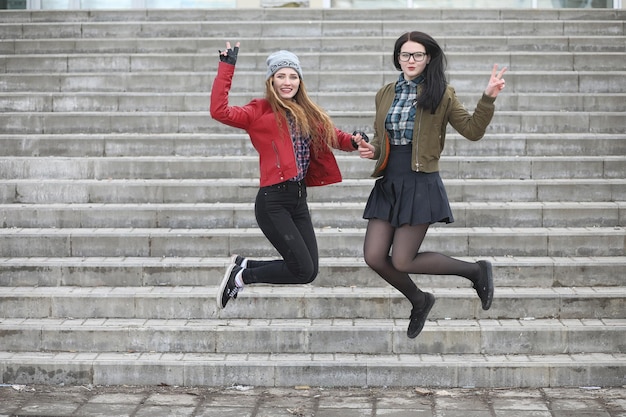 A young hipster girl is riding a skateboard. Girls girlfriends for a walk in city with a skateboard. Spring sports on the street with a skateboard.