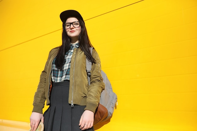 A young hipster girl is riding a skateboard Girls girlfriends for a walk in the city with a skateboard Spring sports on the street with a skateboard