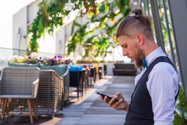 Young hipster groom is worried before the wedding stuck in the phone in privacy