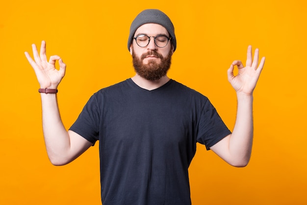 A young hipster is staying calm and relaxed in a zen positioin