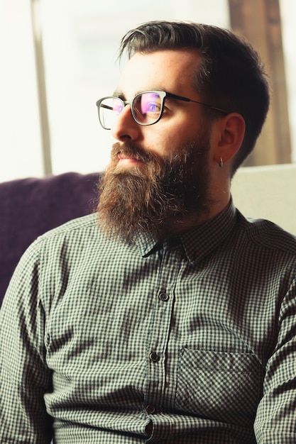 Photo a young hipster male with blue light glasses looking away to camera with a smiling face