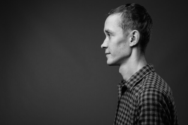  young hipster man against gray wall in black and white