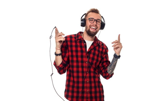 Young hipster man in checkered shirt and glasses wearing earphones looking happy on white background