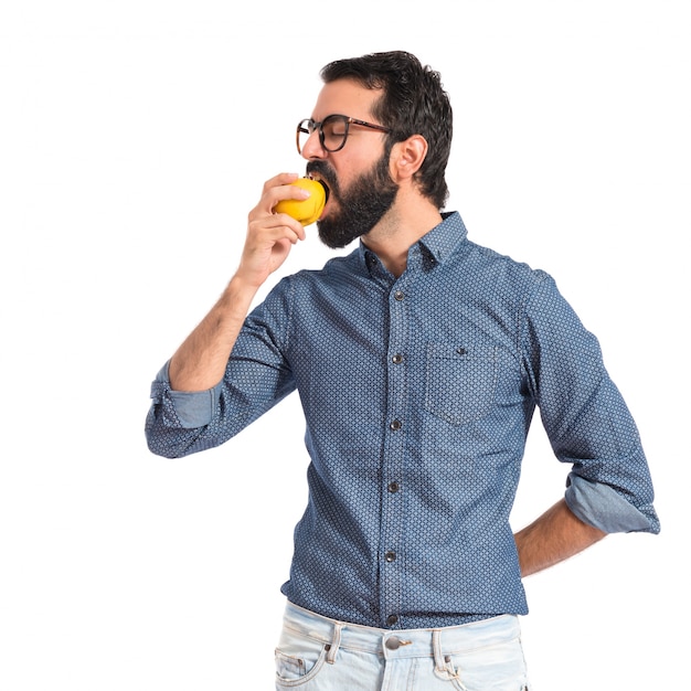 Young hipster man eating apple over white background