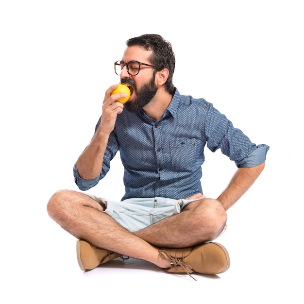 Young hipster man eating apple over white background