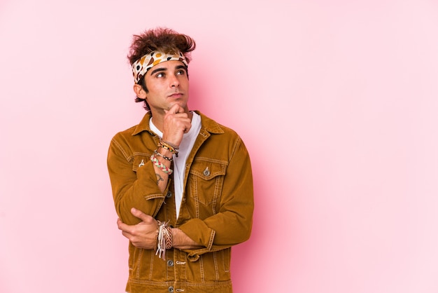 Young hipster man isolated Young man going to a festival looking sideways with doubtful and skeptical expression.