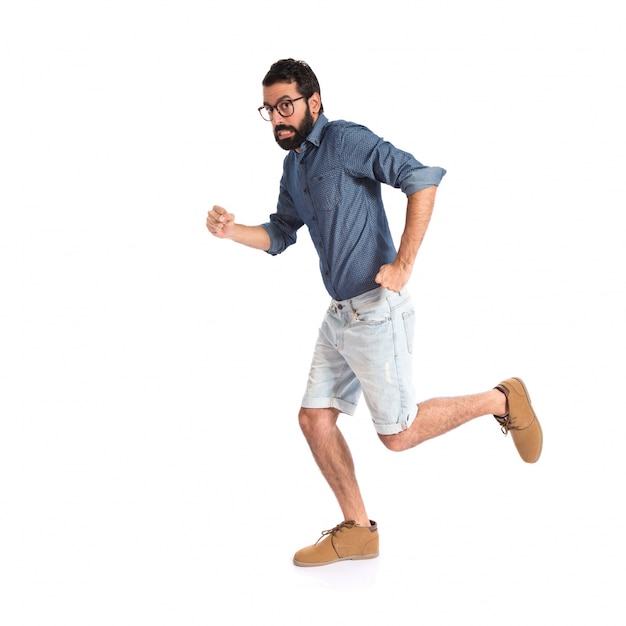 Young hipster man running fast over white background