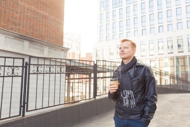 Giovane hipster per strada a bere caffè in una giornata di sole