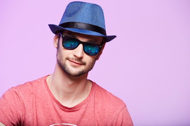 Young hipster man wearing blue hat studio shot over pink\
background