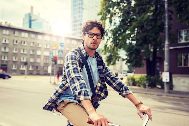 Photo young hipster man with bag riding fixed gear bike