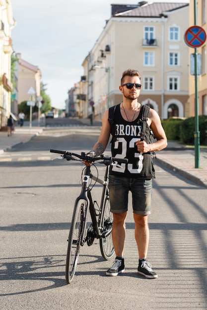 Young hipster man with bicycle walking in the city