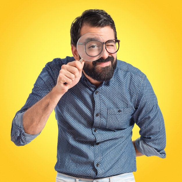 Foto giovane uomo hipster con lente di ingrandimento su sfondo colorato