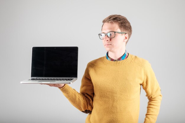 Young hipster presenting your product on a laptop screen isolated on gray background