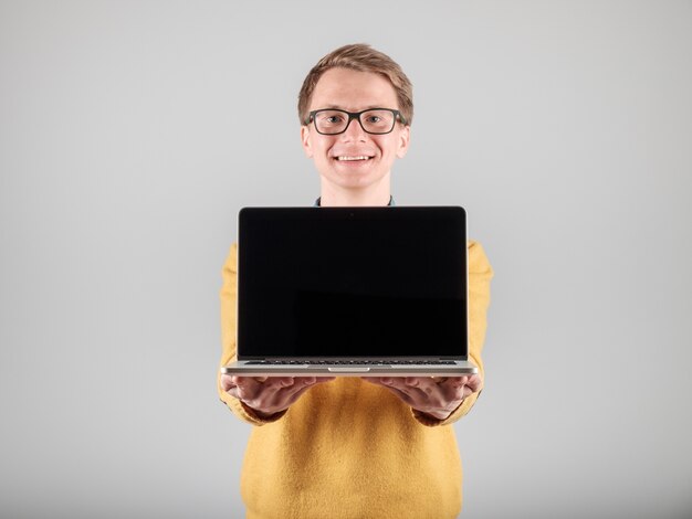 Young hipster showing blank laptop screen isolated