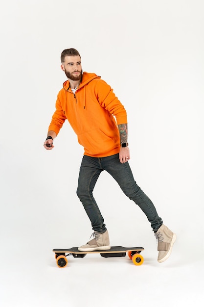 Uomo in stile giovane hipster che fa skateboard su skateboard elettrico