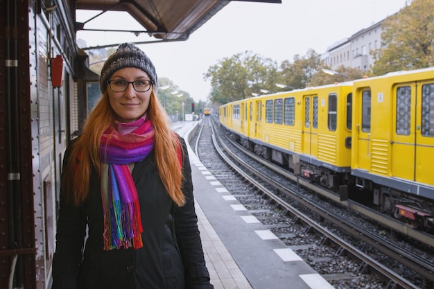 Битник молодая женщина в очках и в теплой одежде на платформе вокзала, портрет