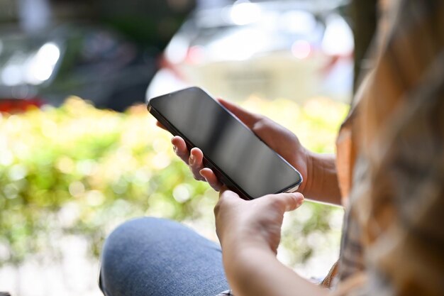 Una giovane donna hipster nel parco utilizzando la sua immagine di primo piano del telefono cellulare intelligente