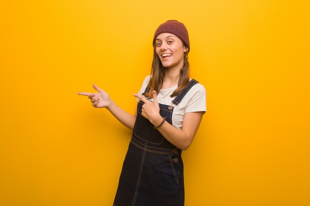 Young hipster woman pointing to the side with finger