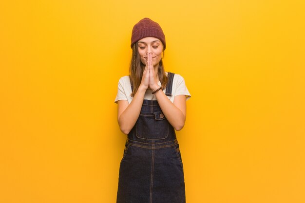 Young hipster woman praying very happy and confident