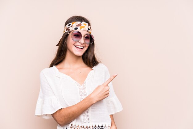 Young hipter caucasian woman isolated smiling and pointing aside, showing something at blank space.