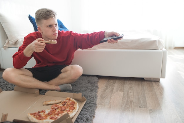 Young in his hands switches TV channels on the remote control