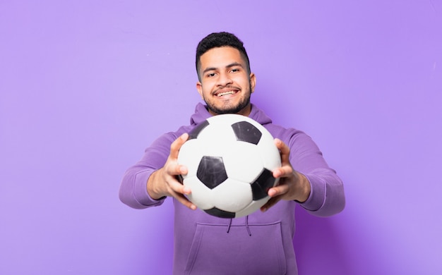 Young hispanic athlete man happy expression and holding a soccer ball