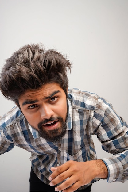 Young hispanic bearded man wearing plaid shirt over white background with positive expression has broad interested smile Look there pleaselooking for something or found something