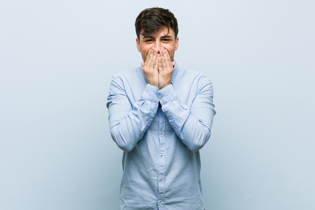 Young hispanic business man laughing about something, covering mouth with hands.