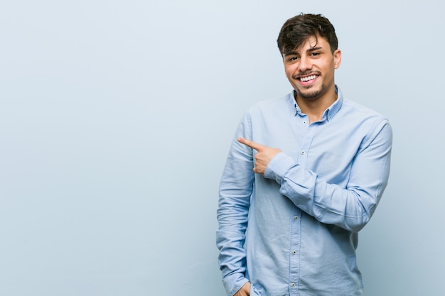 Photo young hispanic business man smiling and pointing aside, showing something blank space.