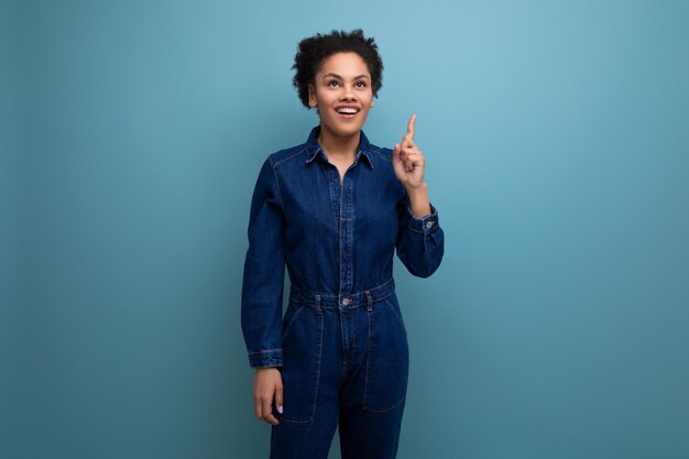 Young hispanic business woman with curly hair dressed in blue denim overalls isolated with copy