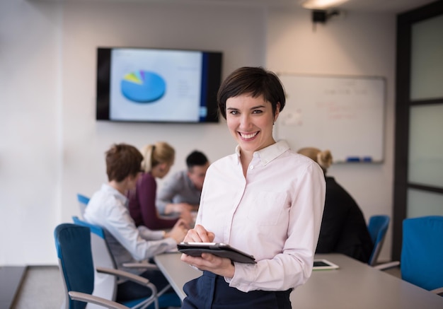 young hispanic businesswoman portrait with  tablet computer at modern startup business office interior, people group on team meeting blured in background