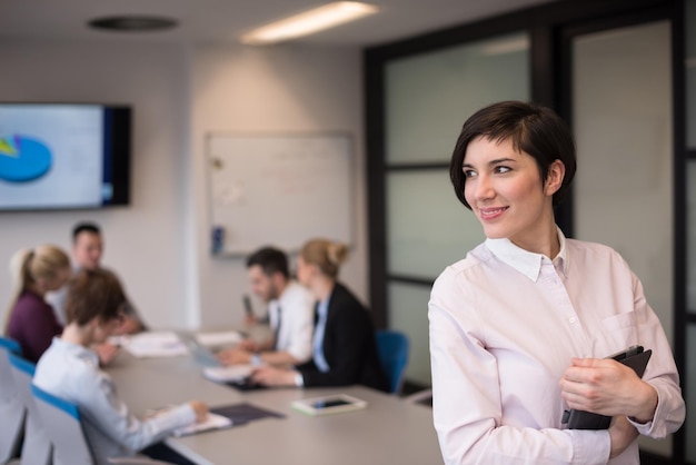 young hispanic businesswoman portrait with  tablet computer at modern startup business office interior, people group on team meeting blured in background