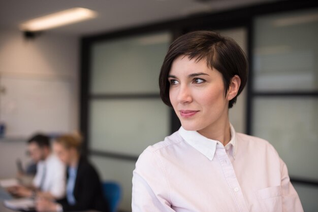 young hispanic businesswoman portrait with  tablet computer at modern startup business office interior, people group on team meeting blured in background