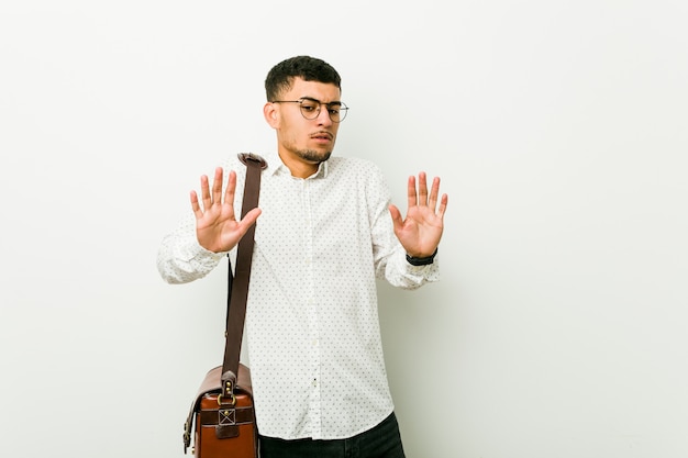 Young hispanic casual business man rejecting someone showing a gesture of disgust.