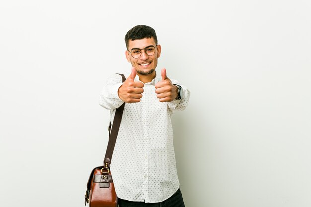 Young hispanic casual business man with thumbs ups, cheers about something