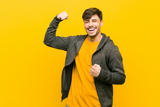 Young hispanic casual man raising fist after a victory, winner concept.