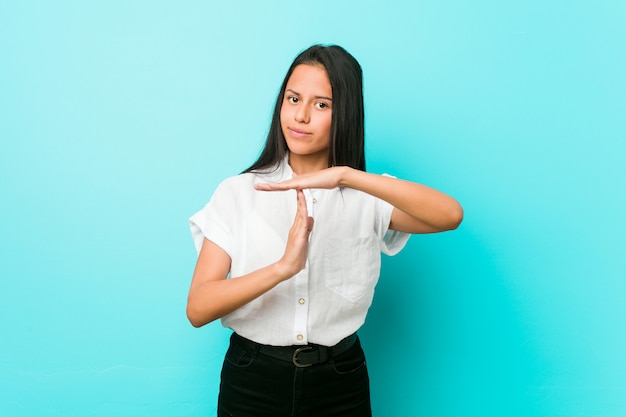 Young hispanic cool woman against a blue wall showing a timeout gesture.