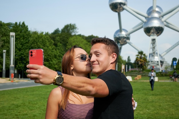 Una giovane coppia ispanica che si fa un selfie all'atomium di bruxelles in belgio