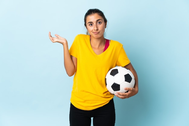 Young hispanic football player woman over isolated on blue wall having doubts while raising hands