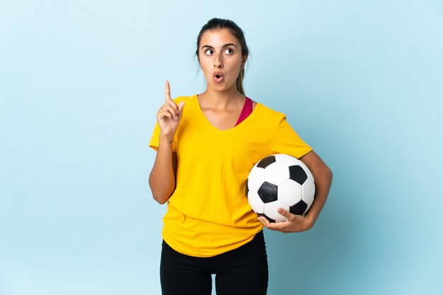 Young hispanic football player woman over isolated on blue wall thinking an idea pointing the finger up