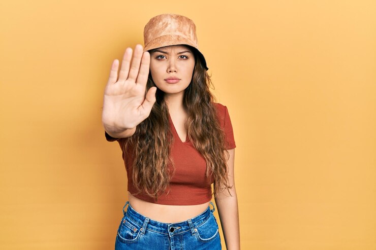 Photo young hispanic girl wearing casual clothes and hat doing stop sing with palm of the hand. warning expression with negative and serious gesture on the face.