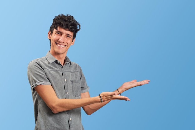 Young Hispanic male teaching towards copy space isolated on blue background