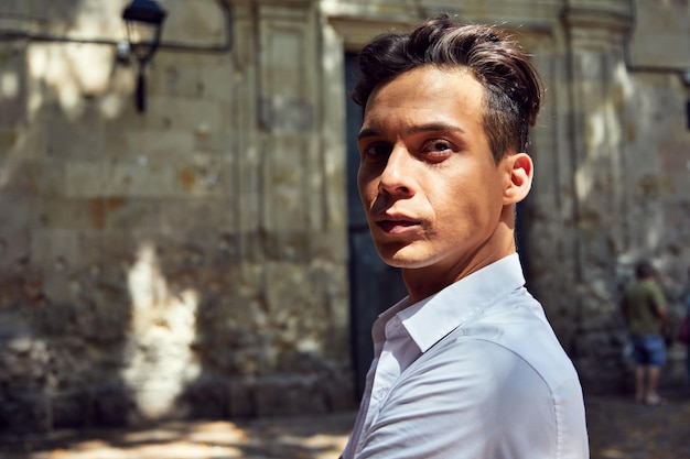 Young Hispanic male wearing a white shirt and walking outdoors