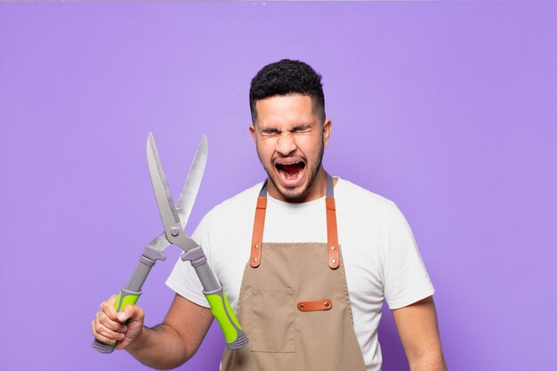 Young hispanic man angry expression. farmer or gardener concept