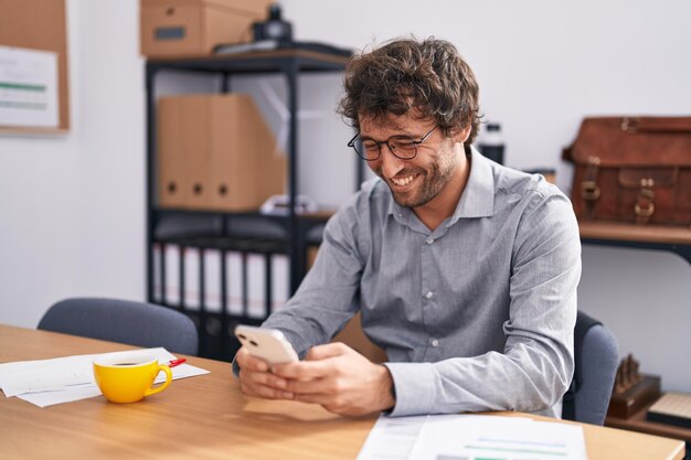 Young hispanic man business worker using smartphone working at office