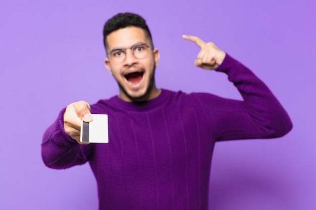 Young hispanic man celebrating successful a victory and holding a credit card