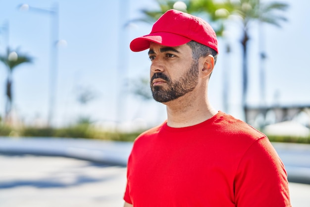 Young hispanic man courier standing with relaxed expression at street