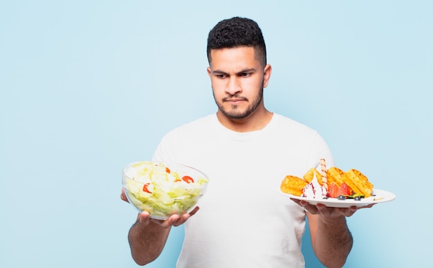 Young hispanic man doubting or uncertain expression and dieting concept